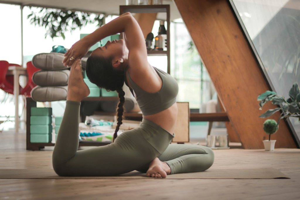 Người phụ nữ thực hiện tư thế yoga Pigeon Pose giúp giãn cơ và giảm mỡ bụng dưới trên thảm tập tại nhà