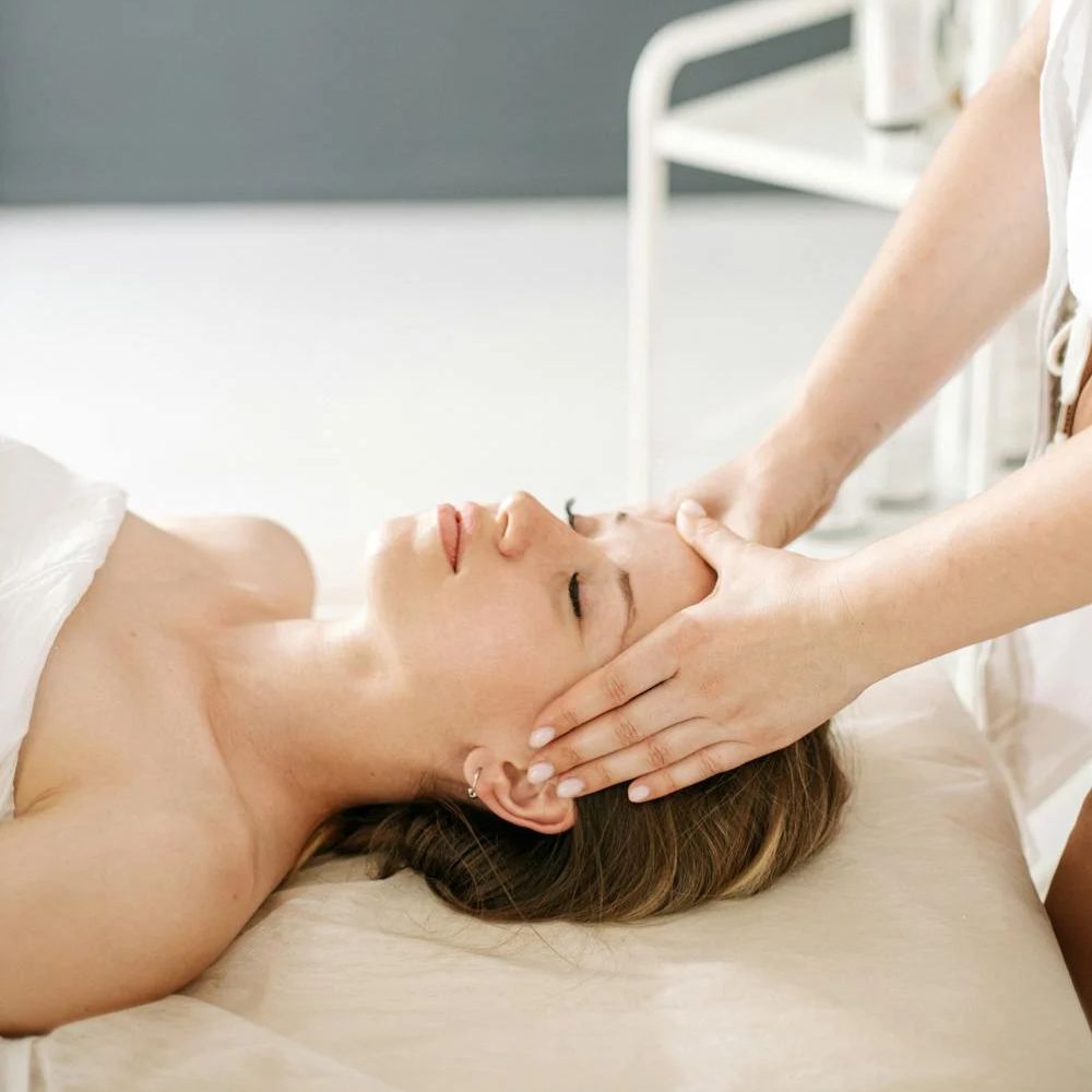 cô gái nằm massage mặt để giảm mặt phù