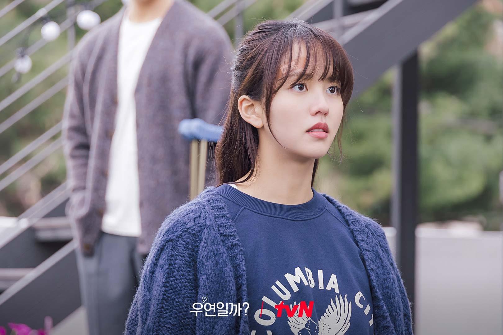 Kim So Hyun mặc áo sweater màu xanh, để tóc mái thưa và buộc nửa đầu