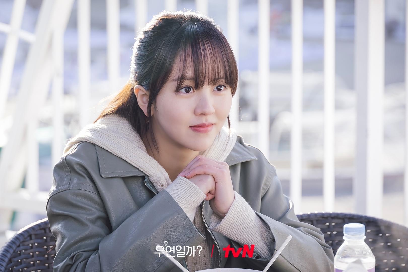 Kim So Hyun mặc áo khoác màu xám, buộc tóc nửa đầu và đan hai tay vào nhau