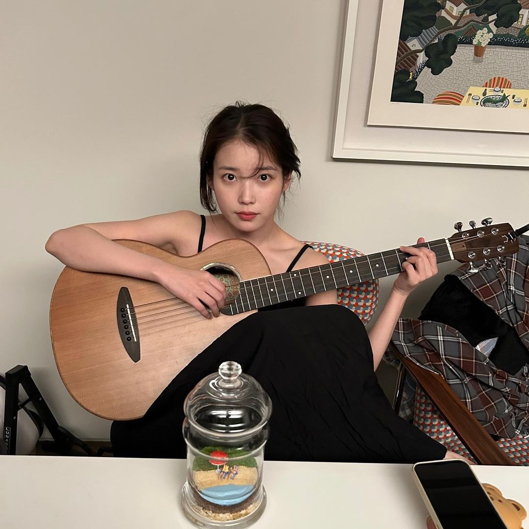 IU đang ngồi ôm đàn guitar